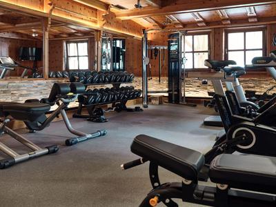 Moderne sportschool met houten muren, spiegels en diverse fitnessapparatuur.