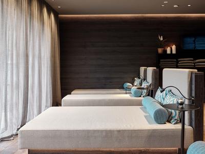 Modern spa with comfortable loungers, soft lighting, and large curtains.