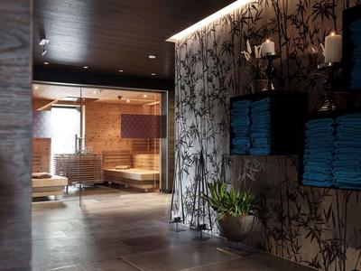 Modern wellness room with wooden furniture, bamboo wallpaper, and stacked blue towels.