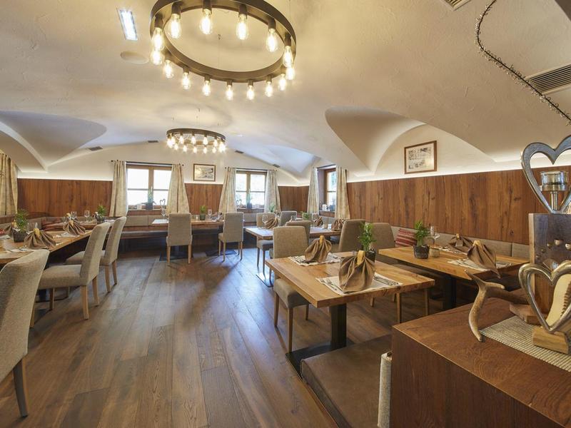 Bright restaurant with wooden floor, chairs, tables, and modern chandeliers.