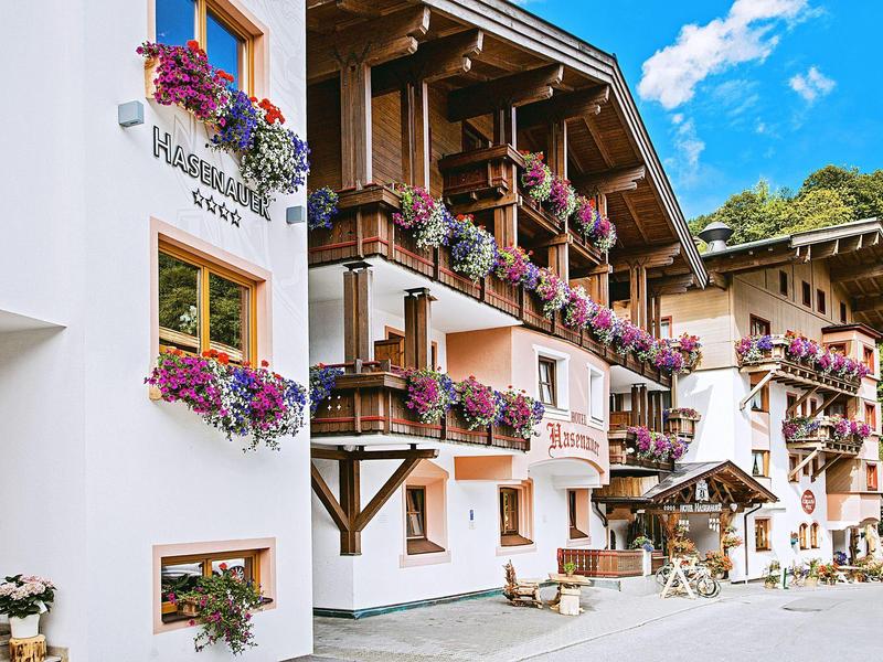Traditional hotel with wooden balconies and colorful flowers under a bright blue sky.