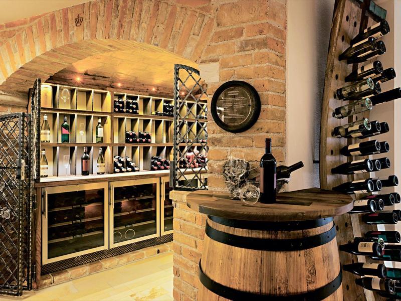 Rustic wine cellar with barrels, wine racks, and warm lighting in a stone vault.