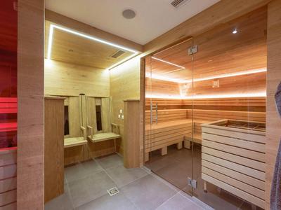 Modern sauna room with wooden walls, benches, and indirect lighting.
