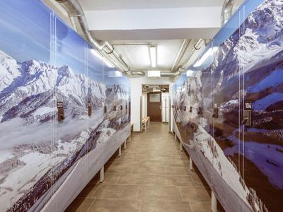 Gang met berglandschap muurschilderingen aan beide zijden in een modern hotel.