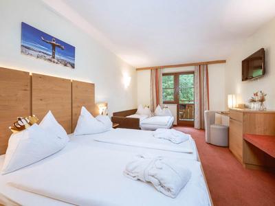 Cozy hotel room with two beds, desk, and balcony overlooking the forest.