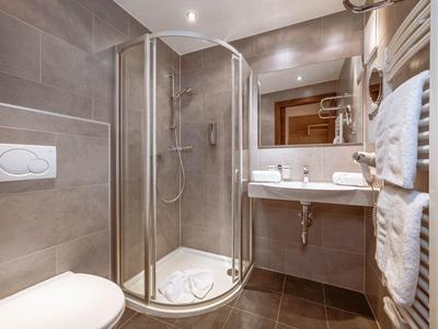 Compact hotel bathroom with corner shower, toilet, and sink with mirror.