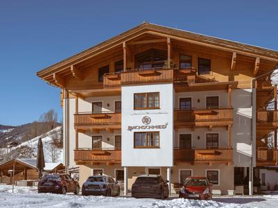 Modern chalet hotel with wooden facade and snowy mountain landscape in the background