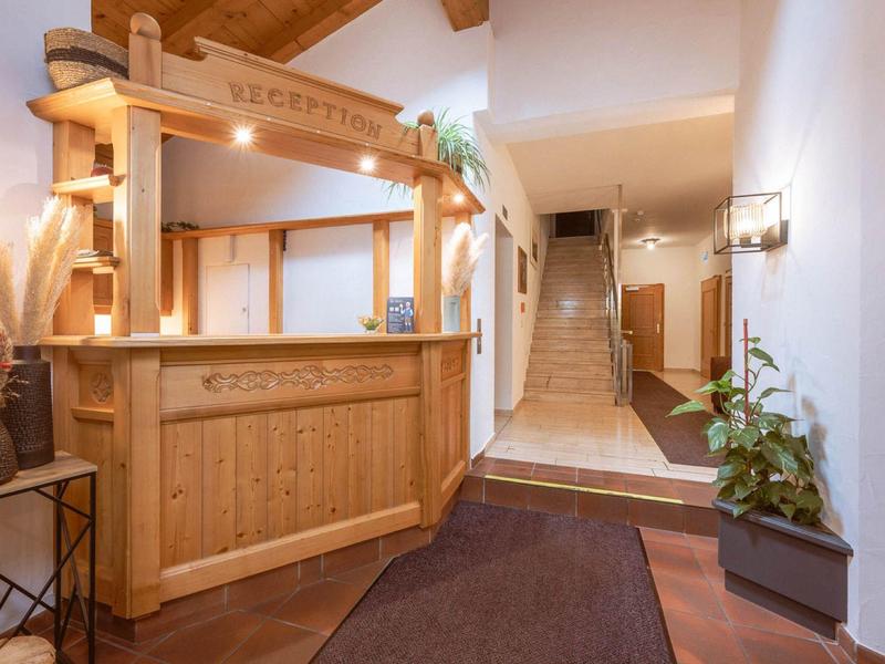 Bright hotel reception with wooden counter and stairs in the background.