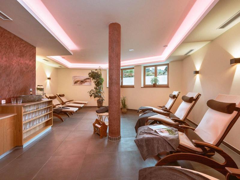 A relaxing wellness room with comfortable lounge chairs, soft lighting, and plants.