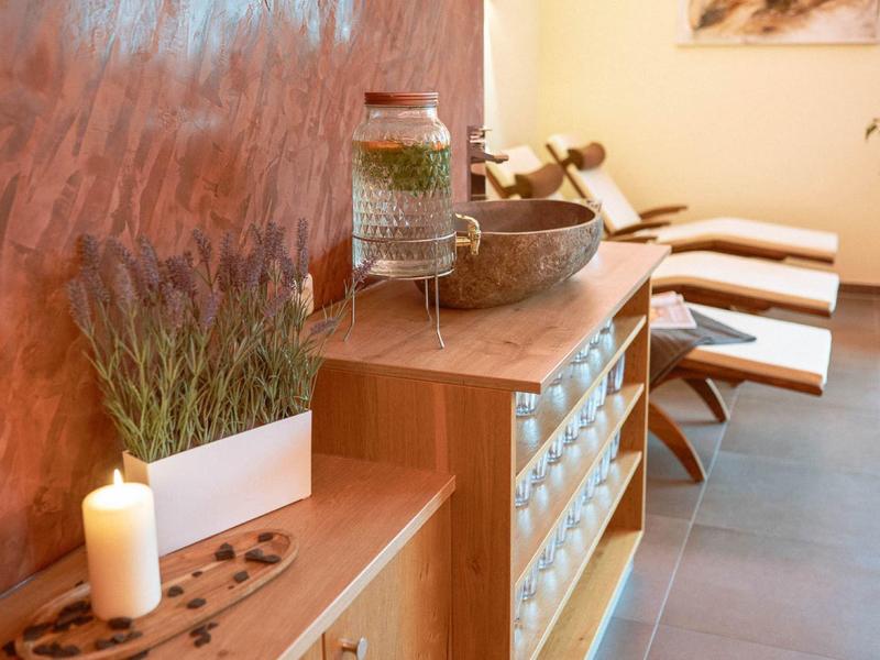 Warm, bright wellness room with wooden furniture, candles, and comfortable lounge chairs.