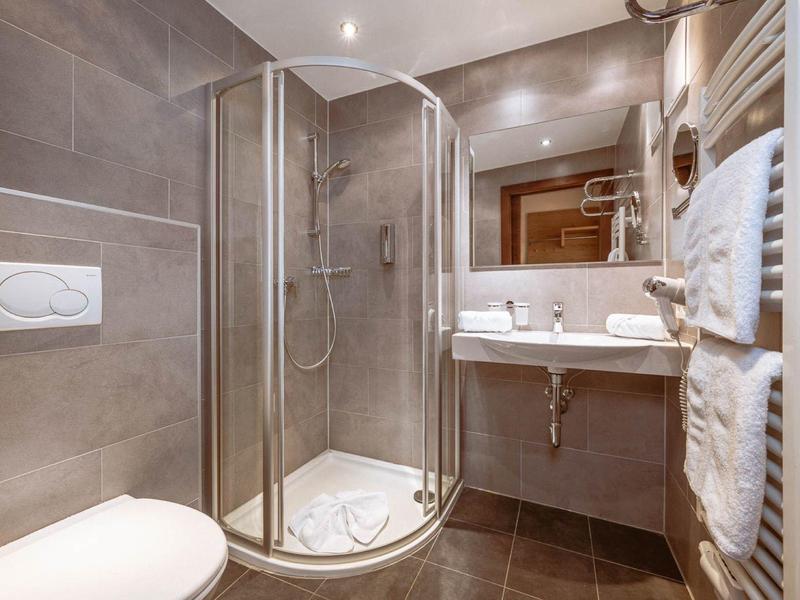 Compact hotel bathroom with corner shower, toilet, and sink with mirror.