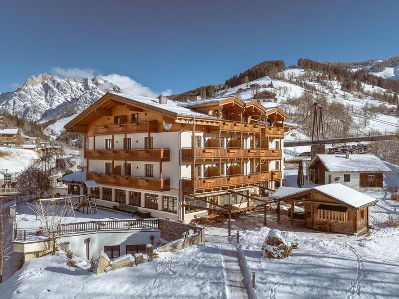 A large wooden hotel building in a snowy mountain landscape under clear sky.