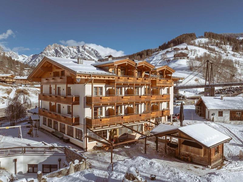 Large alpine-style hotel surrounded by snow with mountains in the background
