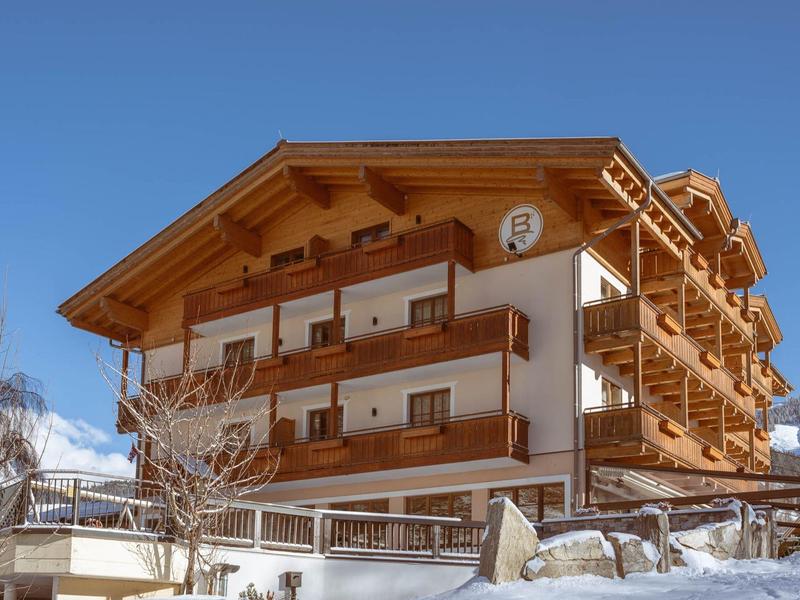 Chalet with wooden balcony and snow in winter under clear sky.