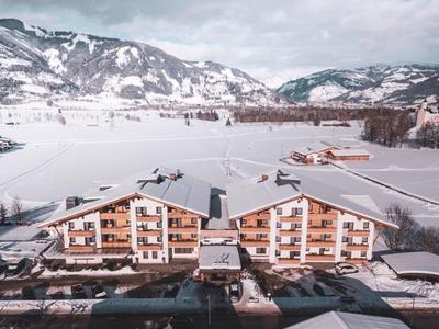 Zweistöckiges Chalet-Hotel in verschneiter Berglandschaft mit Bergen im Hintergrund.