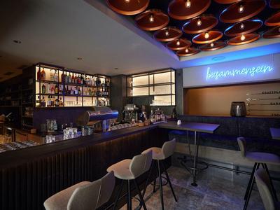 Modern belehrte Bar mit Holztheke, bequemen Stühlen und indirekter blauer Beleuchtung an der Wand.