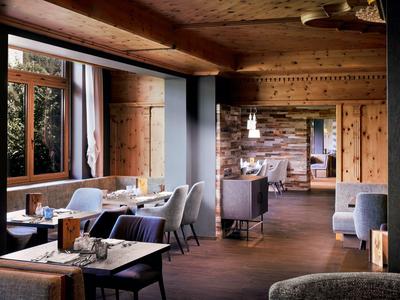 Gemütliches Restaurant mit Holzwänden, großen Fenstern, weißen Stühlen und gedeckten Tischen.