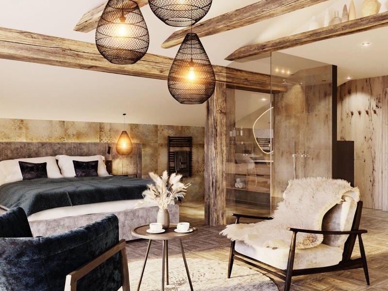 Gemütliches Wohnzimmer mit Holzdecke, grauen Sitzmöbeln, runden Lampen und rustikalem Holzboden.