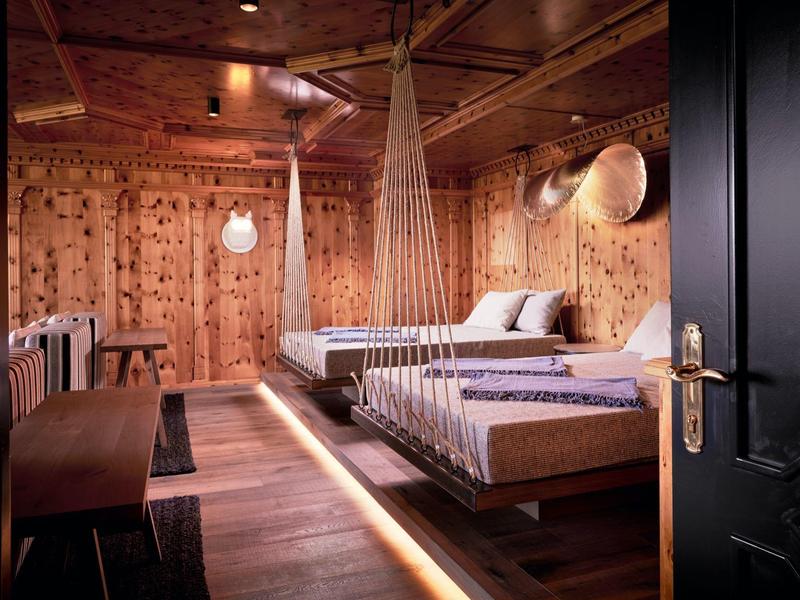 Gemütliches Holzschlafzimmer mit zwei Betten, weichen Decken und warmem Licht unter der Decke.