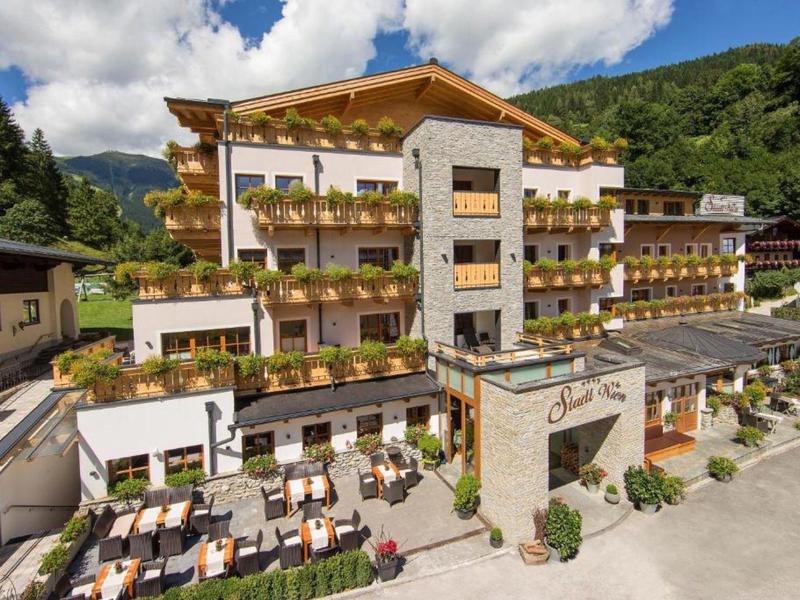 Moderní hotelový komplex se dřevěnými prvky v zelené horské krajině za slunečného počasí.