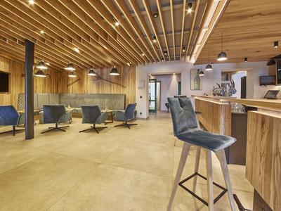 Modern hotel lounge with wooden paneling, blue chairs, and a bar.