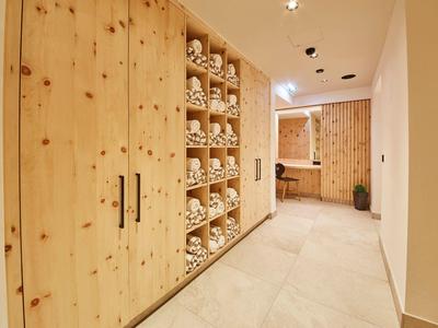 Couloir avec armoires en bois et étagères remplies de serviettes dans un hôtel moderne.