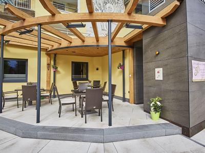 Terrazza dell'hotel con struttura in legno, tavoli e sedie sotto un'area coperta