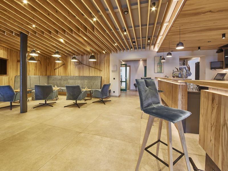 Espace lounge d'hôtel moderne avec accents en bois et sièges bleus confortables.