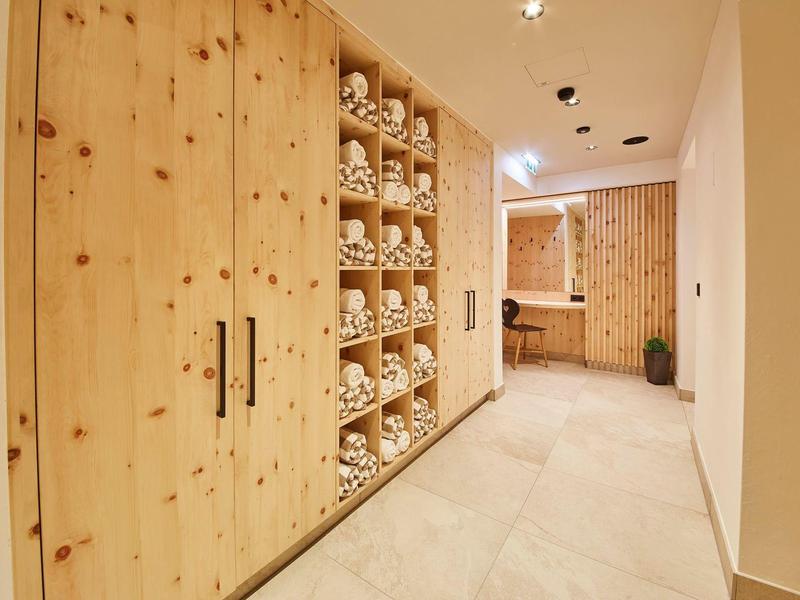 Couloir avec armoires en bois et étagères remplies de serviettes dans un hôtel moderne.