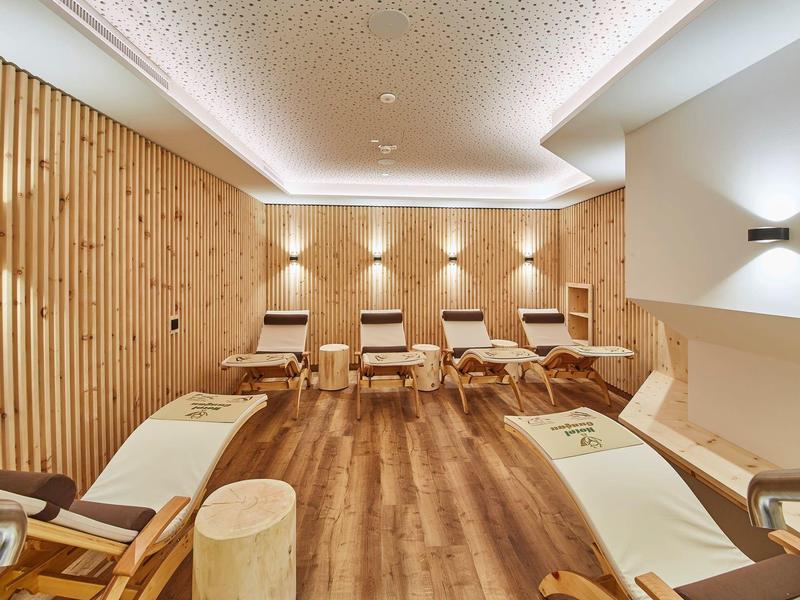 Salle de détente avec fauteuils confortables, panneaux en bois et éclairage tamisé.