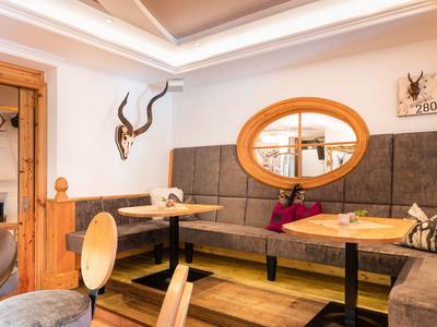 Příjemný hotelový bar s čalouněnými lavicemi, dřevěnými stoly a dekorativními doplňky.