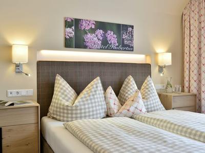 Przytulny pokój hotelowy z podwójnym łóżkiem, kratkowymi pościelami i kwiatową dekoracją na ścianie.