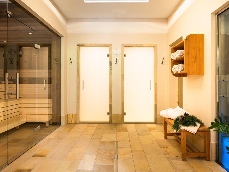 Jasna strefa wellness z sauną, pokojem relaksacyjnym i drewnianymi leżakami.