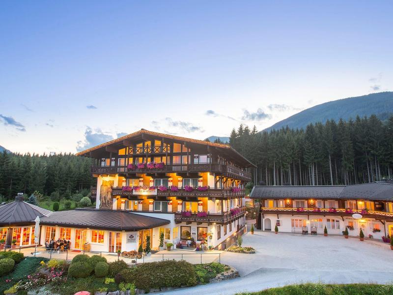 Nowoczesny hotel z drewnianą konstrukcją w zalesionym górskim krajobrazie o zmierzchu.