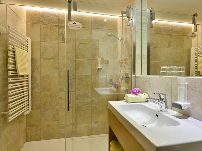 Nowoczesna łazienka hotelowa z prysznicem i zadbanym umywalką.