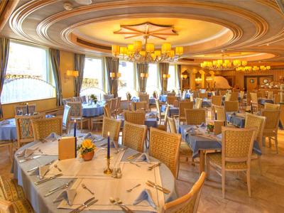 Ristorante elegante con tavolo rotondo, candele e sedie sotto una luce calda.