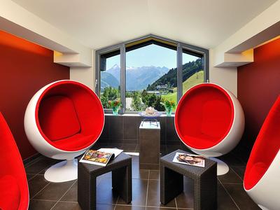 Lounge moderna con poltrone sferiche rosse e vista sulle montagne attraverso una grande finestra