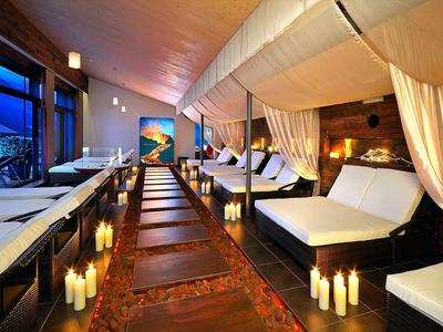 Elegantní spa pokoj s pohodlnými postelemi, záclonami a svíčkami.