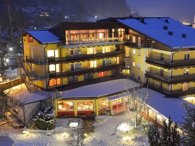 Osvětlený hotel s balkony v zasněžené horské krajině v noci.
