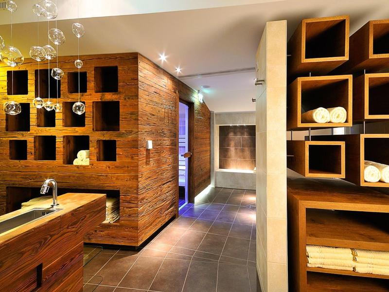 Moderní interiér spa s dřevěnými policemi, ručníky a tlumeným osvětlením.