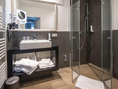 Moderne Dusche mit Glasabtrennung, Untertischwaschbecken, großem Spiegel und Handtüchern in hellem Bad.