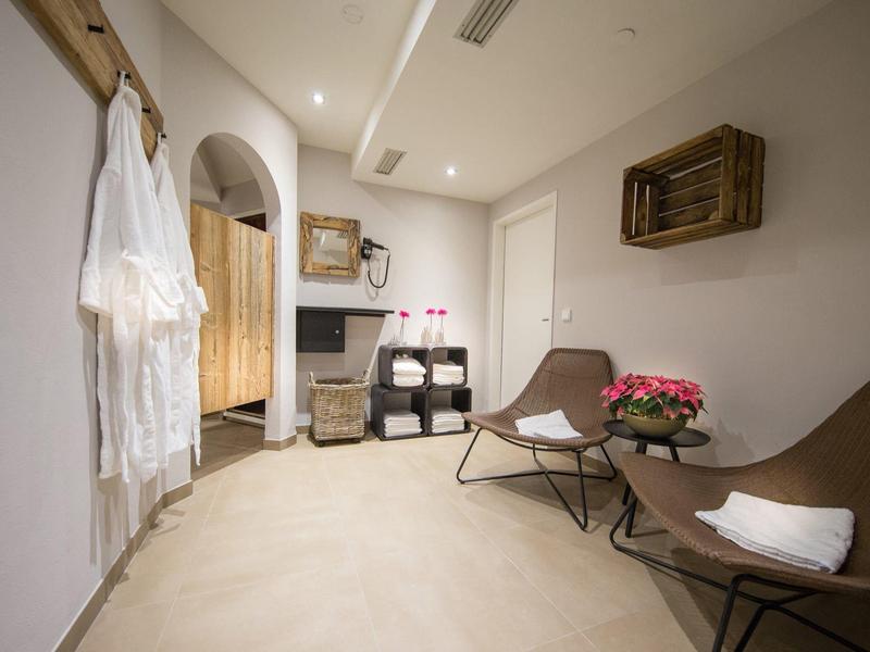 Heller, moderner Warteraum mit zwei Stühlen, Beistelltisch, Blumen und sanfter Beleuchtung.