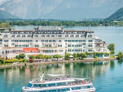 Hotel sul lago con battello passeggeri e montagne sullo sfondo sotto un cielo azzurro