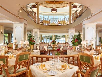 Elegantní, světlá jídelna s dekorovanými stoly a židlemi v hotelu.