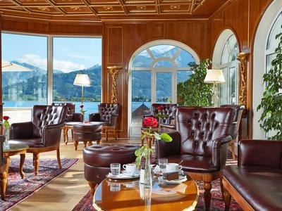 Elegantní hotelový pokoj s dřevěným obložením, koženými křesly a velkými okny s výhledem na hory.