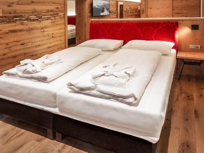 Camera d'hotel moderna con due letti singoli, rivestimento in legno e testiera imbottita rossa