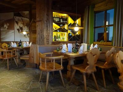 Accogliente sala da pranzo con sedie e tavolo in legno, decorata con bottiglie di vino e vista dalla finestra.