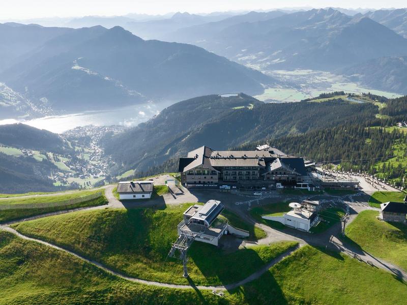 Complexe hôtelier sur plateau montagneux vert avec vue sur les vallées et montagnes environnantes.