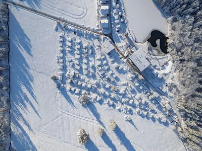 Vista aérea de un complejo vacacional nevado con cabañas y bosque