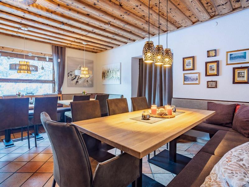 Acogedora zona de comedor con mesa de madera, sillas y sofá bajo techo de madera.